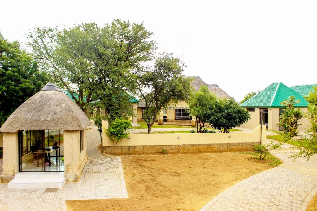 Cette chambre offre une vue sur une maison dotée d'un toit de chaume. dans l'établissement Zoe Bush Lodge, à Pretoria