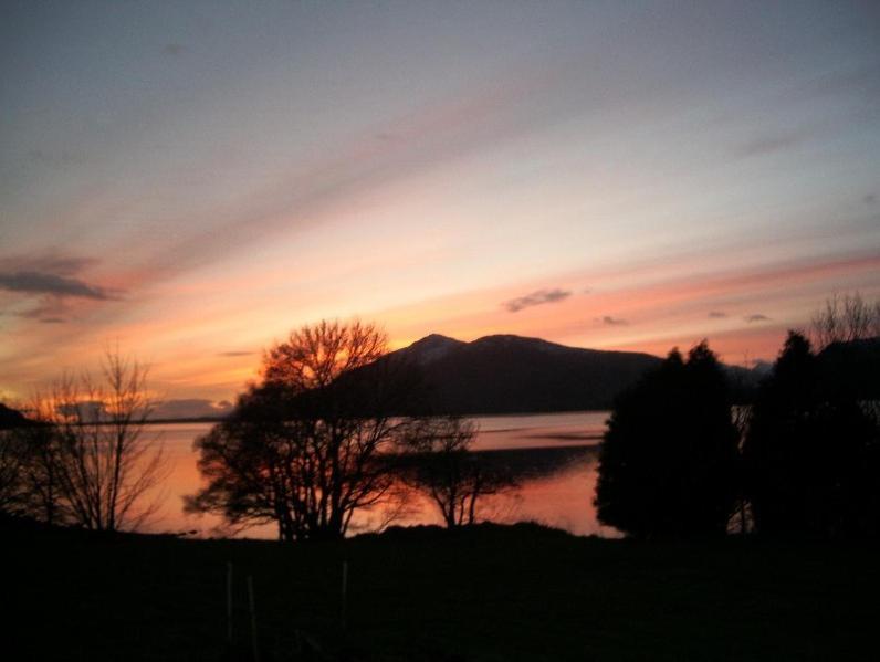 a sunset over a body of water with a mountain at Campfield House in Fort William
