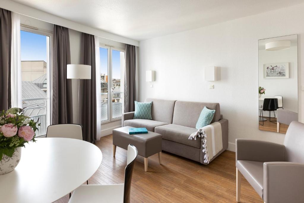 a living room filled with furniture and a table at Citadines Bastille Marais Paris in Paris