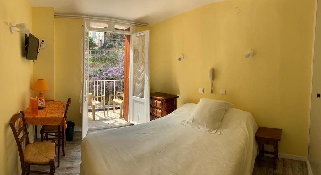 een slaapkamer met een bed, een tafel en een raam bij Hôtel des Bains et des Gorges in Amélie-les-Bains-Palalda