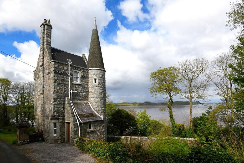 an old stone church with a steeple and a lake at Tower Lodge in Auchencairn