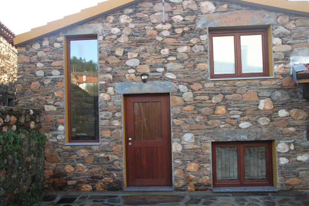 ein Steinhaus mit einer Holztür und Fenstern in der Unterkunft Casa Do Quelho in Janeiro de Cima