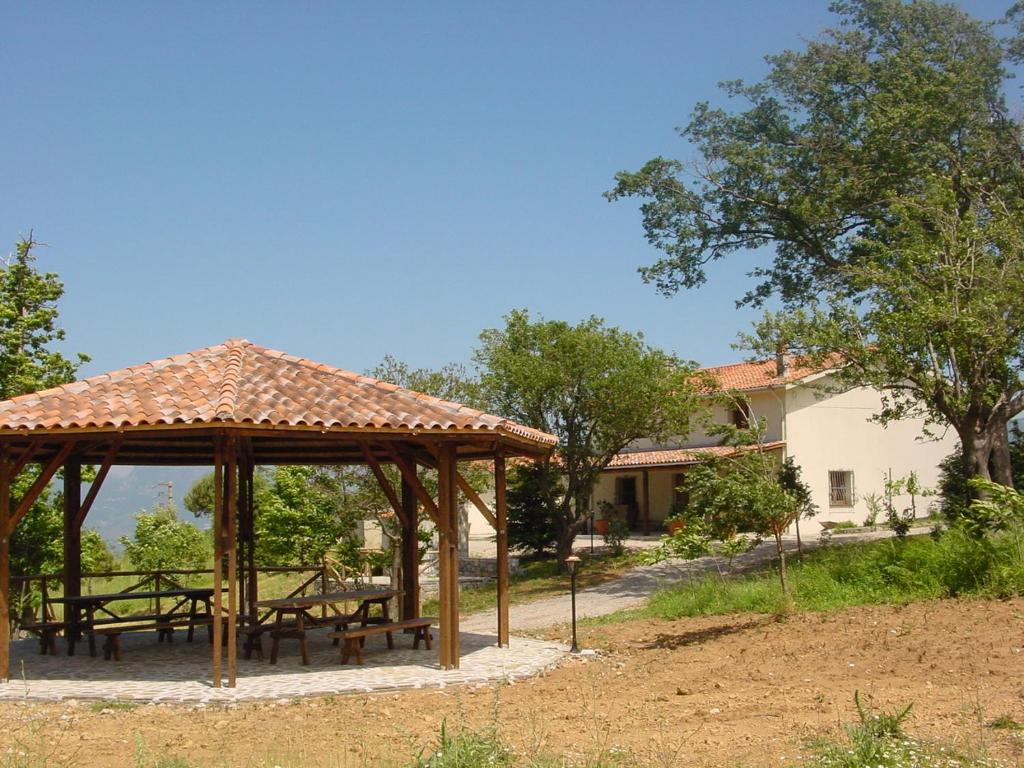 a gazebo with picnic tables in front of a house at Agriturismo Collevento in Trecchina