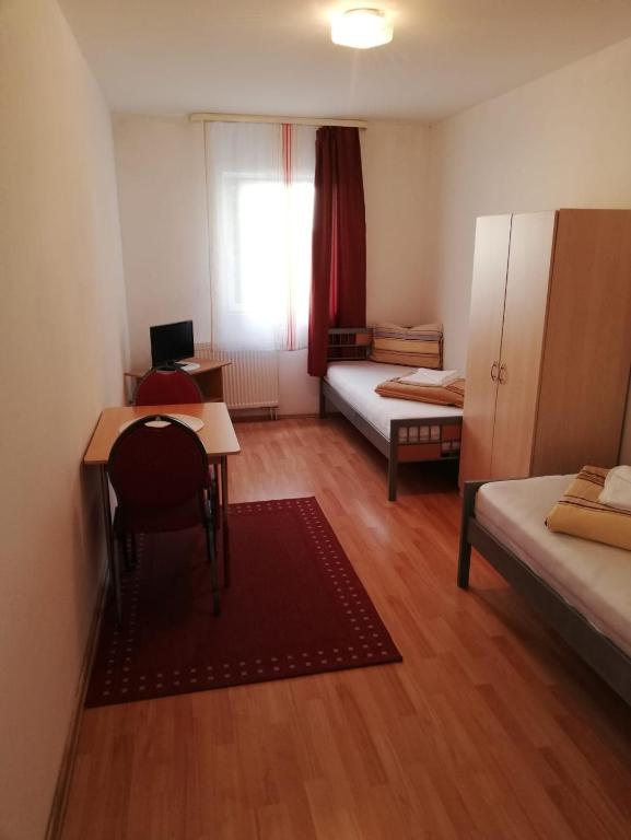 Habitación pequeña con escritorio, cama y mesa. en Pension Feldschlössl, en Ingolstadt