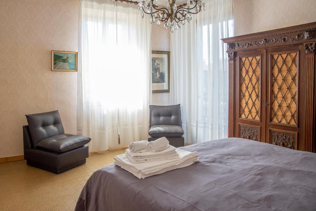 a bedroom with a bed with two chairs and a chandelier at Bed & Roses Meni in La Morra