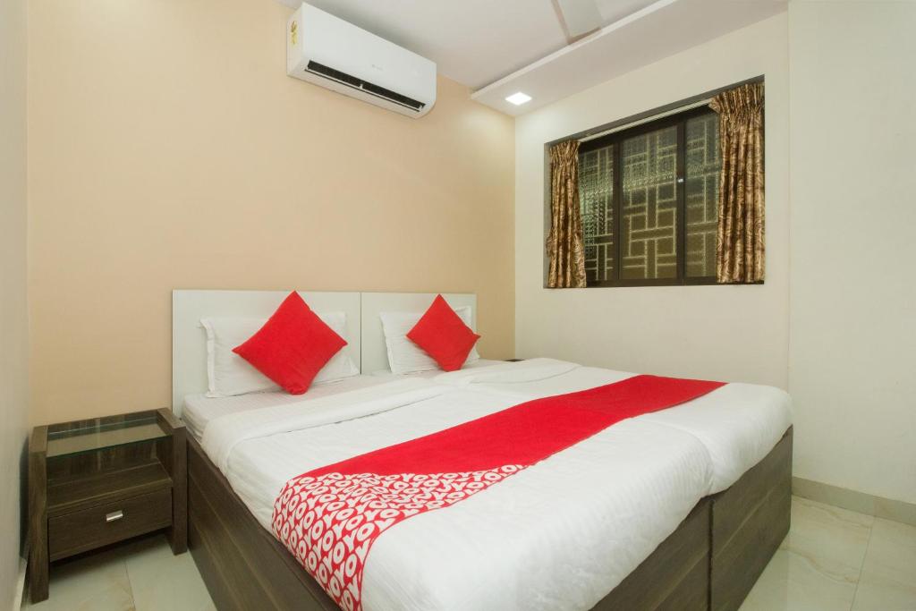 a bedroom with a large bed with red pillows at Hotel Nest Inn in Mumbai
