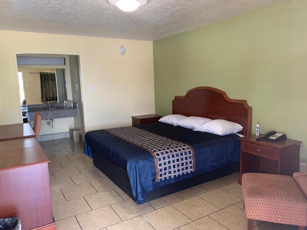 Habitación de hotel con cama y silla en Texas Inn Beaumont, en Beaumont