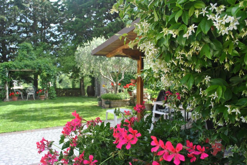 einen Garten mit rosa Blumen und einem Holzschirm in der Unterkunft Villa Le Casaline in Messenano