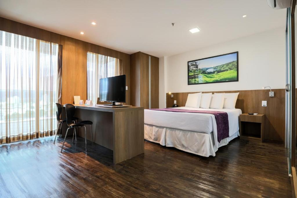 a hotel room with a bed and a flat screen tv at San Diego Governador Valadares in Governador Valadares