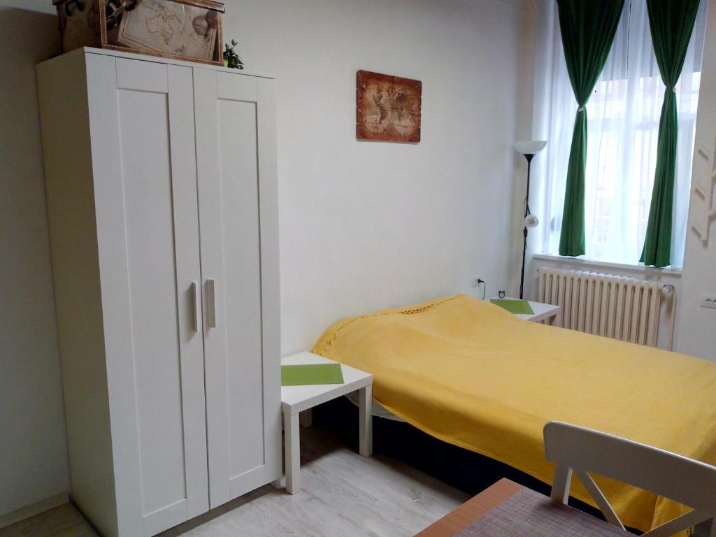 a small bedroom with a yellow bed and a cabinet at Studio Jolie in Novi Sad