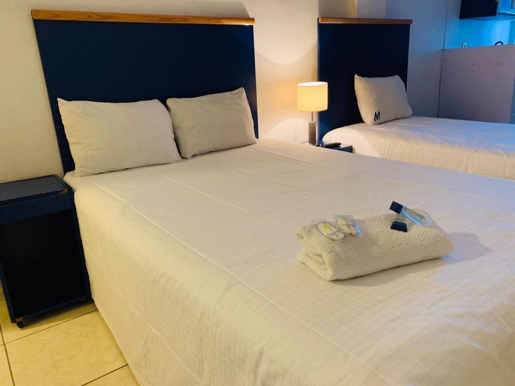 a hotel room with a large white bed with towels on it at Hotel H Americas in Guadalajara