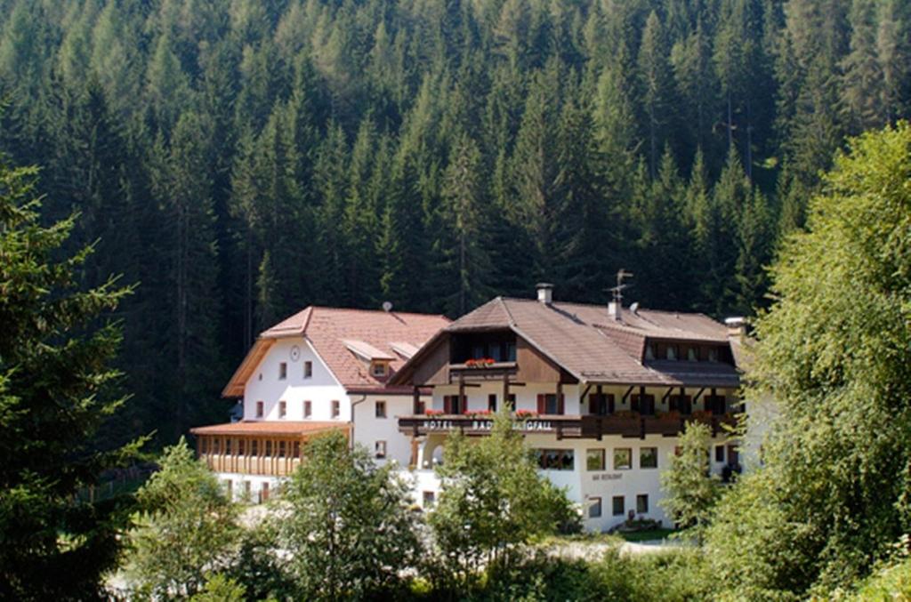 a large white house in the middle of a forest at Hotel Bad Bergfall in Valdaora