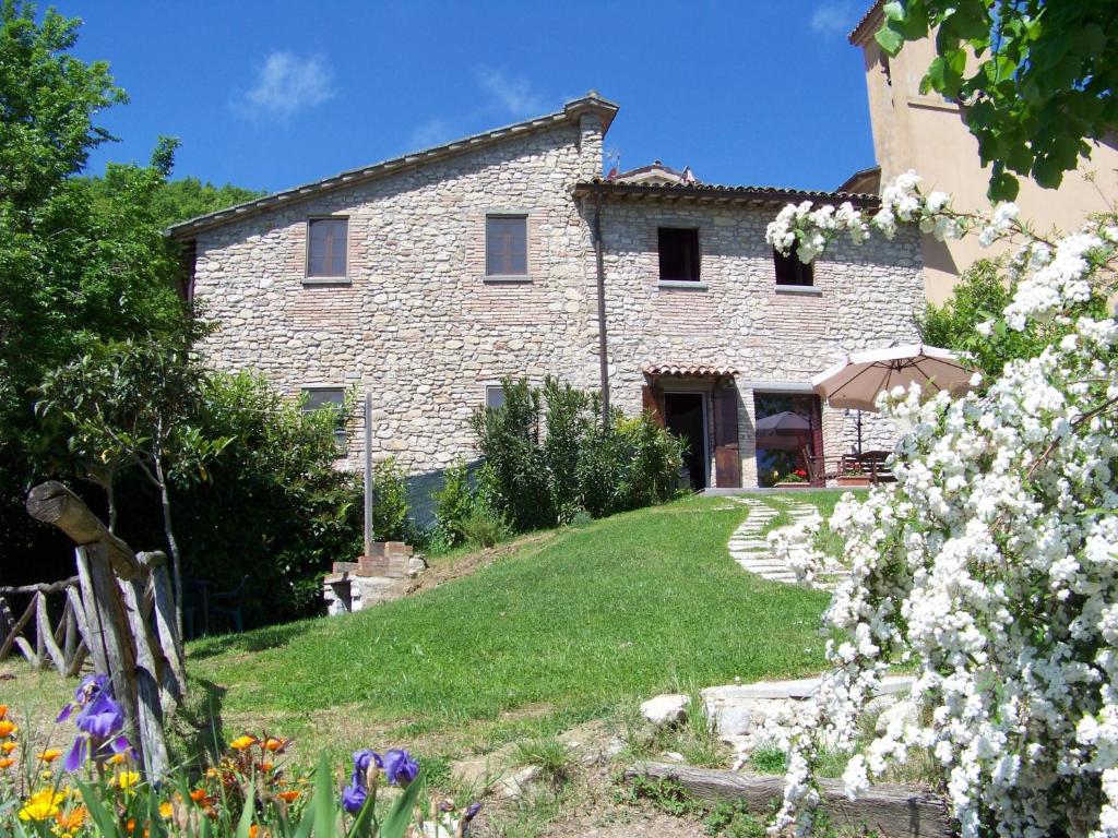 une maison en pierre avec des fleurs devant elle dans l'établissement Appartamenti Valdipetrina, à Città di Castello