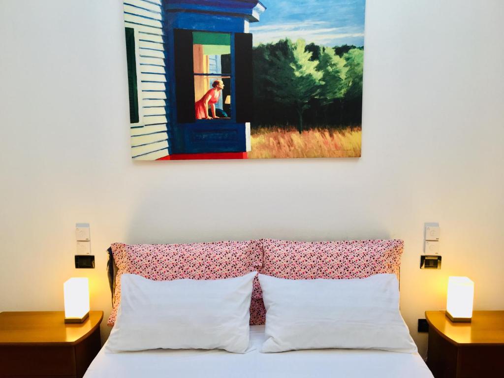 波隆那的住宿－Casa Santo Stefano，挂在床上的画作,上面有两个床头柜和一张带两个床头柜的床
