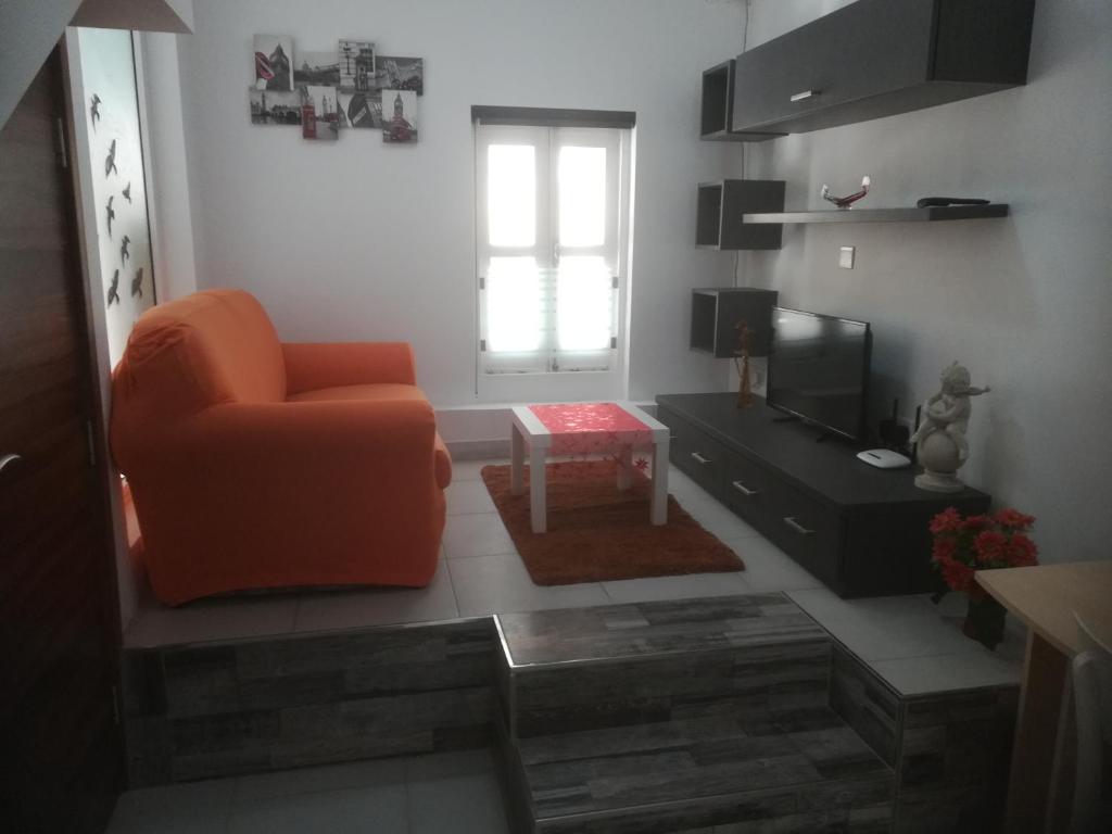 a living room with an orange chair and a television at Nice and cosy apartment close to seafront in Sliema