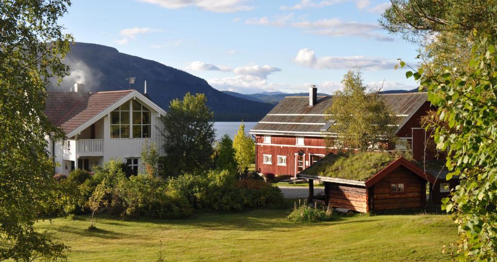 a house and a barn with a mountain in the background at Fossumsanden Camping og Hytter in Fyresdal