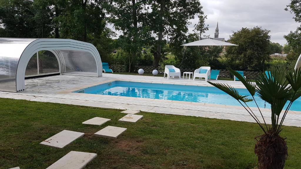 a swimming pool with a cover next to a yard at Manoir des Turets in Yvré-lʼÉvêque