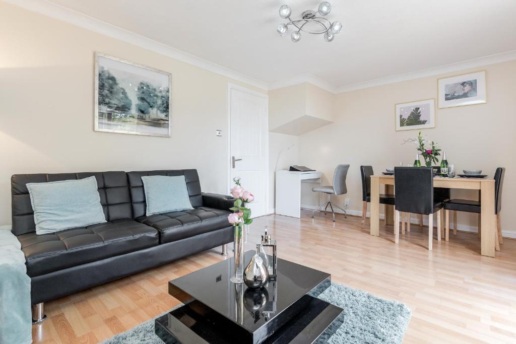 a living room with a black couch and a table at Thurrock, Grays -Spacious 3bd 3bath House Lakeside in Grays Thurrock