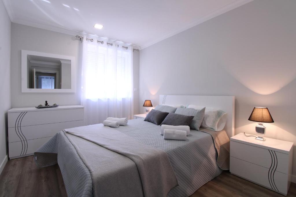 a white bedroom with a large bed and two night stands at Casa Cervo Artes in Vila Nova de Cerveira