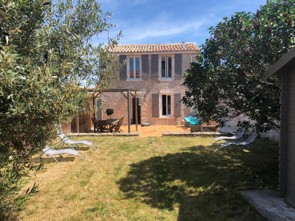 a house with a yard with chairs in front of it at Le Petit Nid Cosy in Esnandes