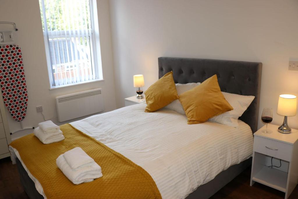 een slaapkamer met een groot bed met gele kussens bij Modern Newgate Apartments - Convenient Location, Close to All Local Amenities in Stoke on Trent