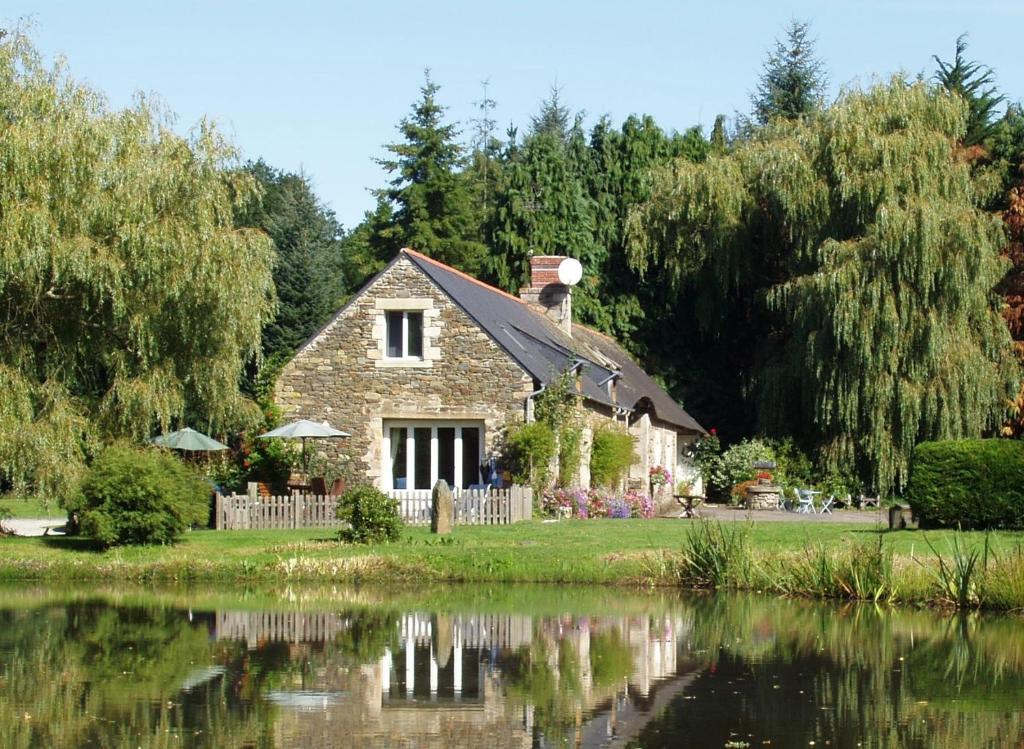 a stone cottage next to a body of water at Gites De Lenvos in Pontivy