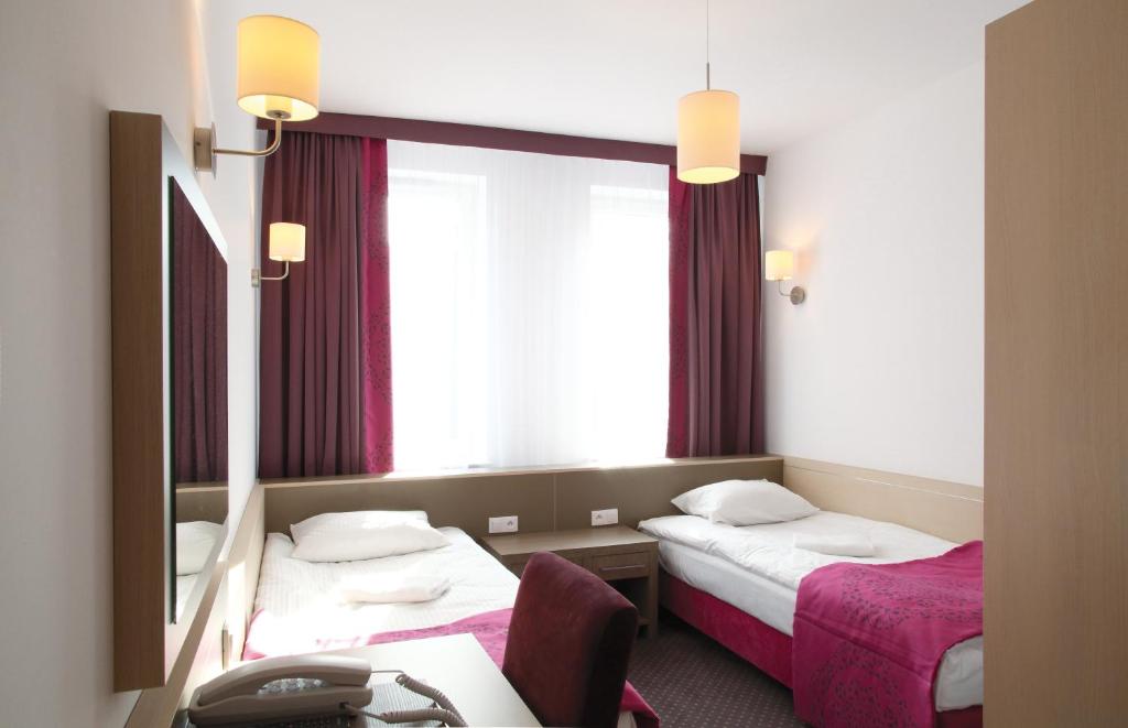 a hotel room with two beds and a mirror at Arche Hotel Siedlce in Siedlce
