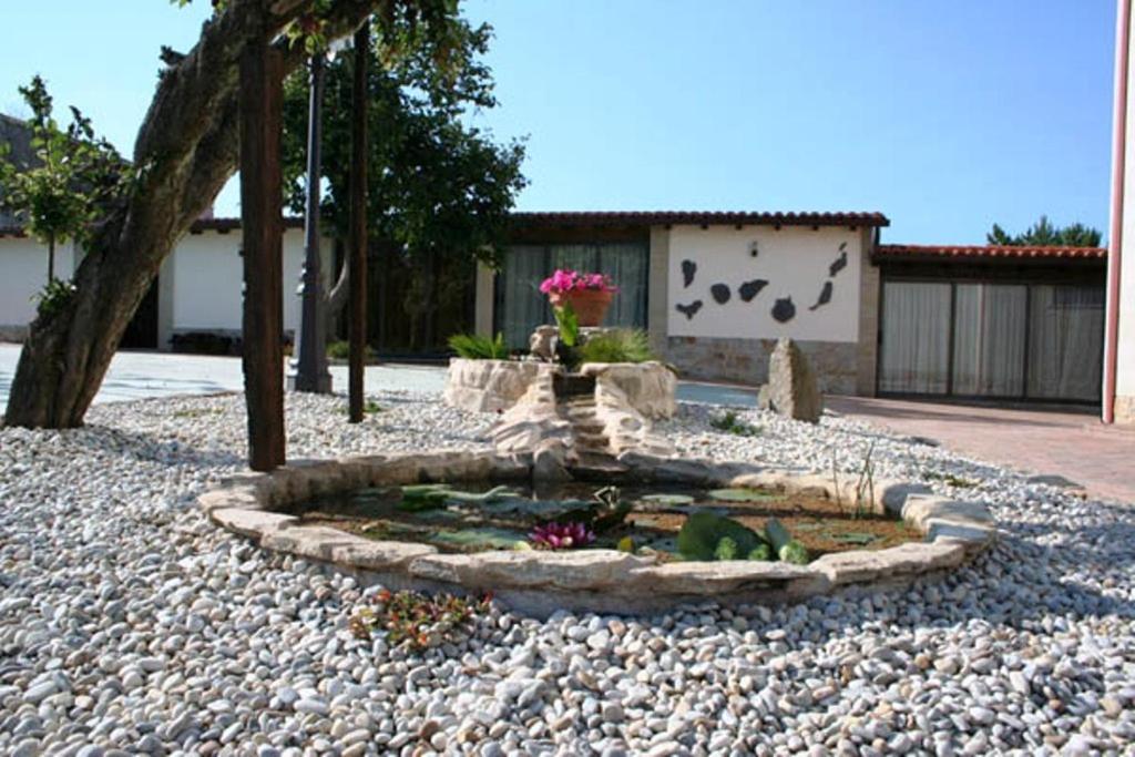 a small garden with a fountain in a gravel yard at Hotel Rural Neixon in Boiro