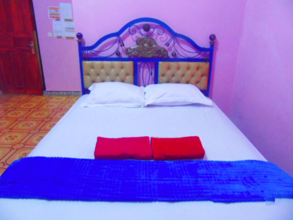 a bed with two red pillows on top of it at Aini Home Stay in Ternate
