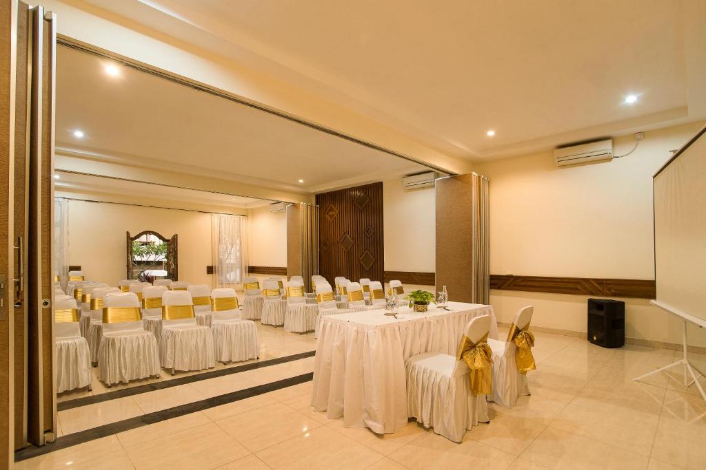 a banquet hall with white tables and chairs and a mirror at Sri Phala Resort & Villa in Sanur