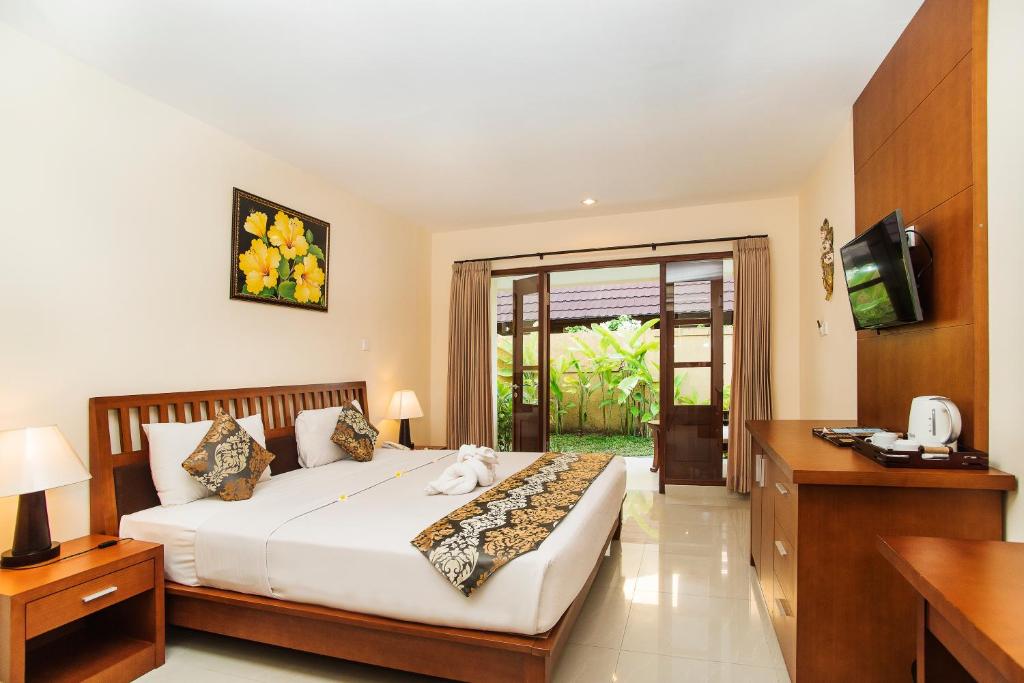 a hotel room with a bed and a television at Sri Phala Resort & Villa in Sanur