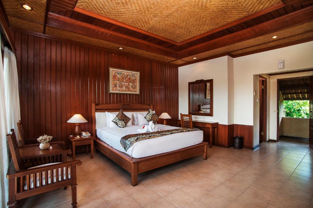 a bedroom with a large bed and wooden walls at Sri Phala Resort & Villa in Sanur