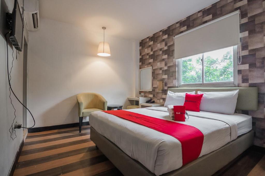 a bedroom with a large bed with a red blanket at RedDoorz Plus near Mangga Besar Station 2 in Jakarta