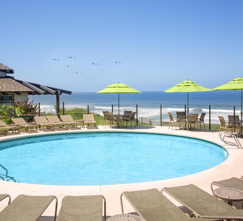 a swimming pool with chairs and umbrellas and the ocean at WCH at Wave Crest Resort in Del Mar