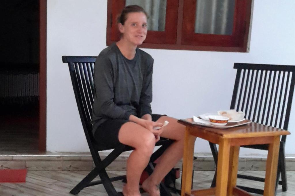 une femme assise sur une chaise à côté d'une table dans l'établissement Hotel Chanaya, à Ambanpola