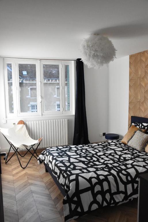 a bedroom with a bed and a chair and windows at LE SELECT DE BROU in Bourg-en-Bresse