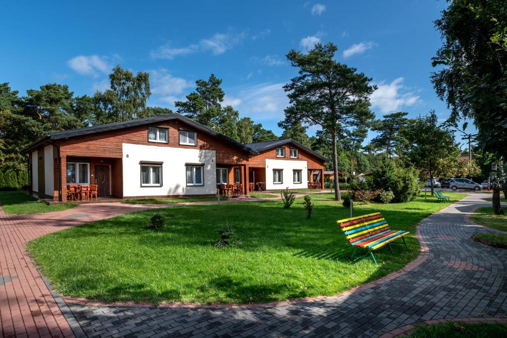 a house with a bench in the grass at Ośrodek Wczasowy Wodnik in Ostrowo