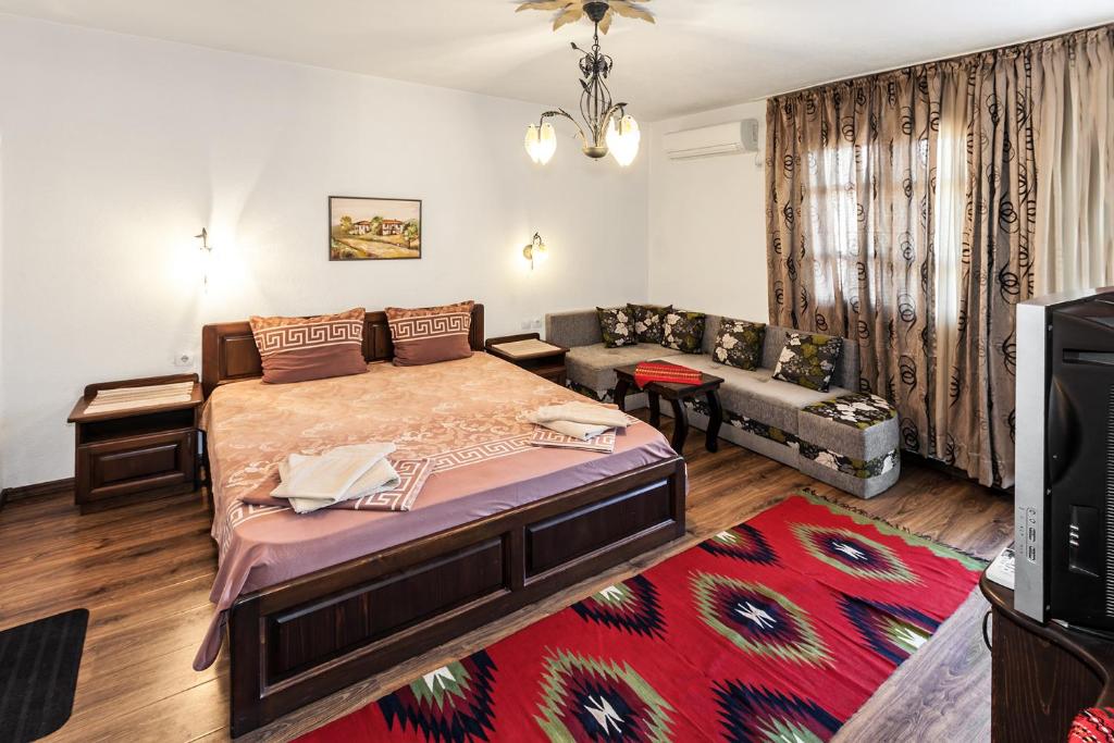 サンダンスキにあるKeremidchieva Kushta Guest Houseのベッドルーム(大型ベッド1台、ソファ付)