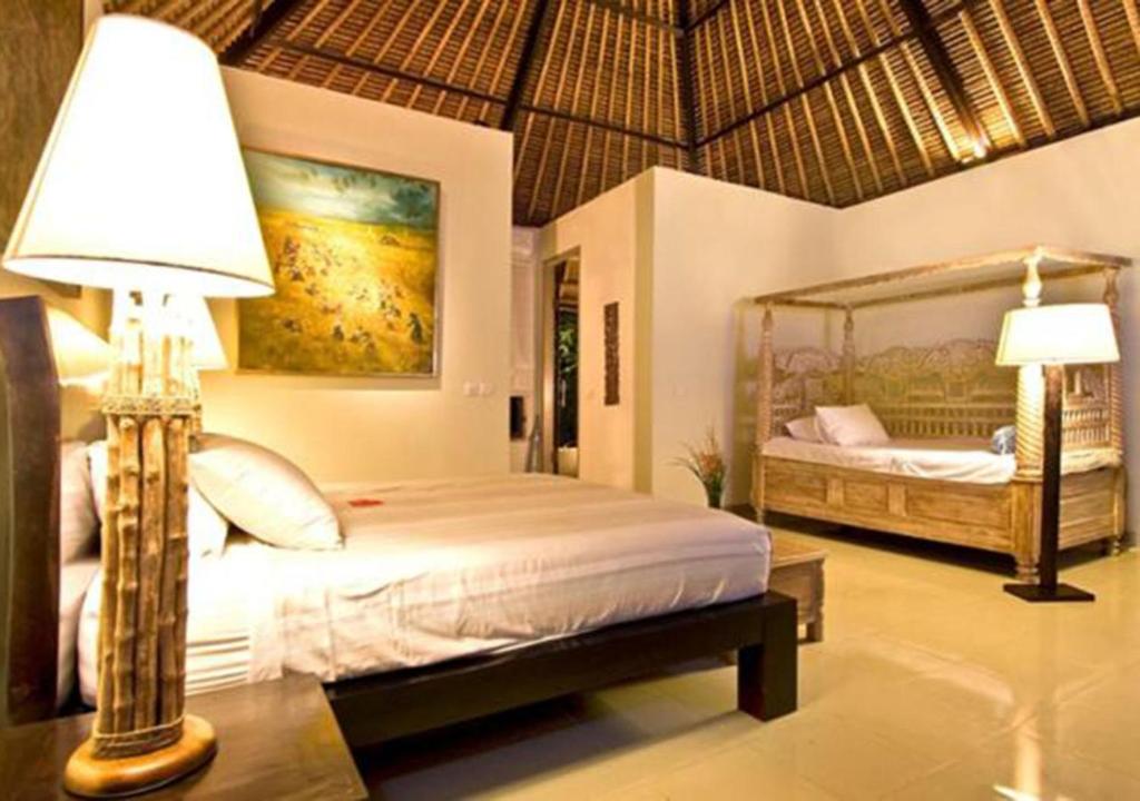 een slaapkamer met een bed, een lamp en een spiegel bij Puri Darma Agung Villa in Ubud