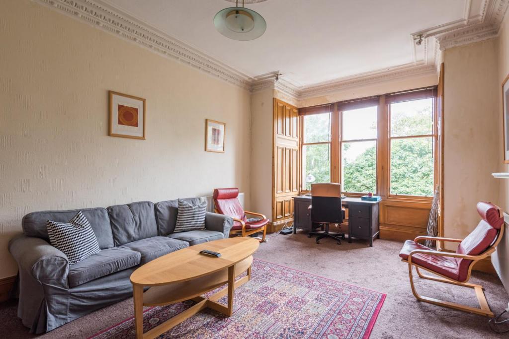 een woonkamer met een bank en een tafel bij 3 bed overlooking meadows park in Edinburgh