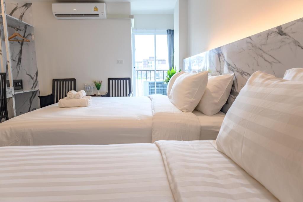 two beds in a hotel room with a teddy bear on them at Donmueang Place Hotel - SHA Plus in Bangkok