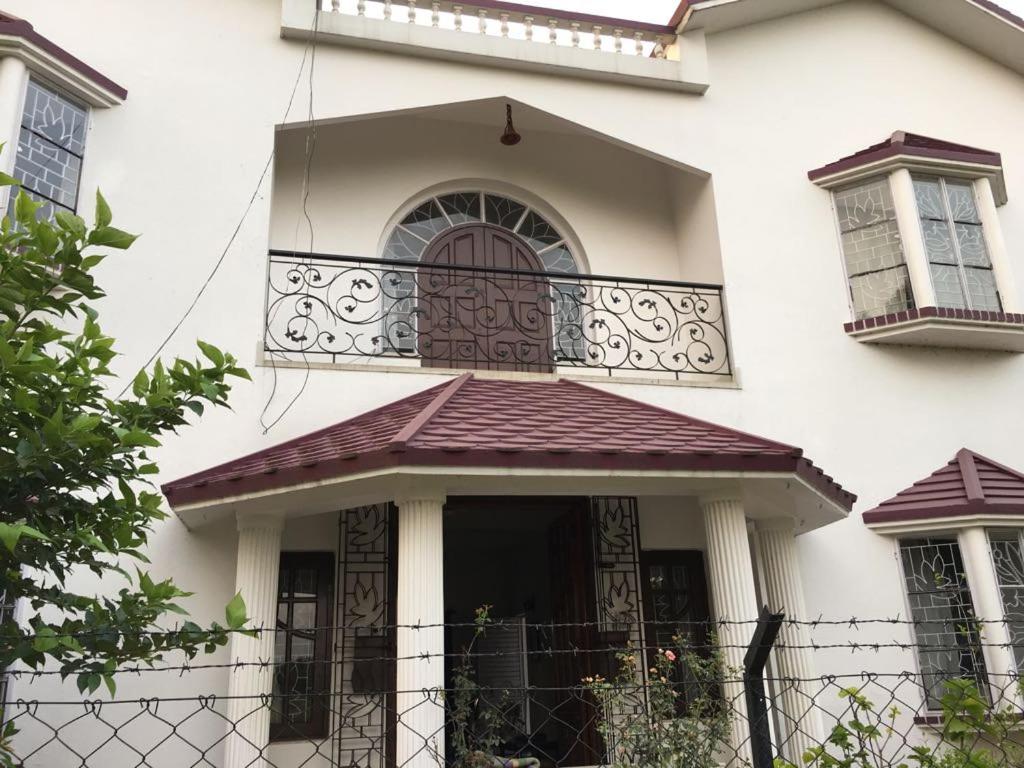 a white house with a balcony and a fence at Preyoshi in Bolpur