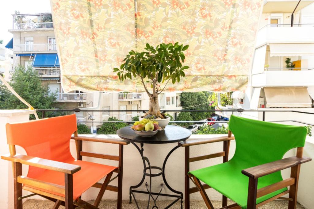a balcony with chairs and a table with a tree on it at Beautiful appartment under Akropolis! in Athens