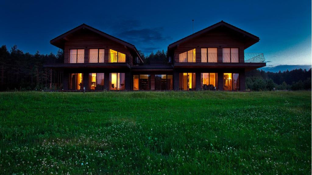 una casa en un campo con las luces encendidas en Ami Residence, en Druskininkai