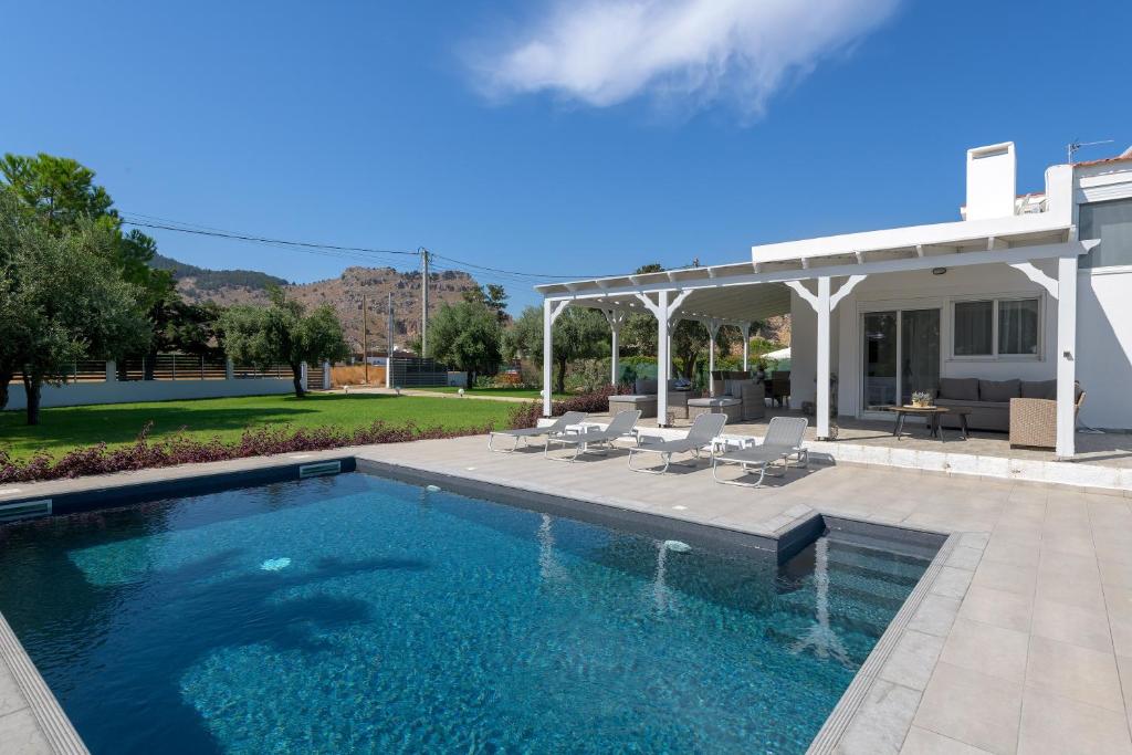a swimming pool with chairs and a house at Casa Bianca Villa in Kolymbia