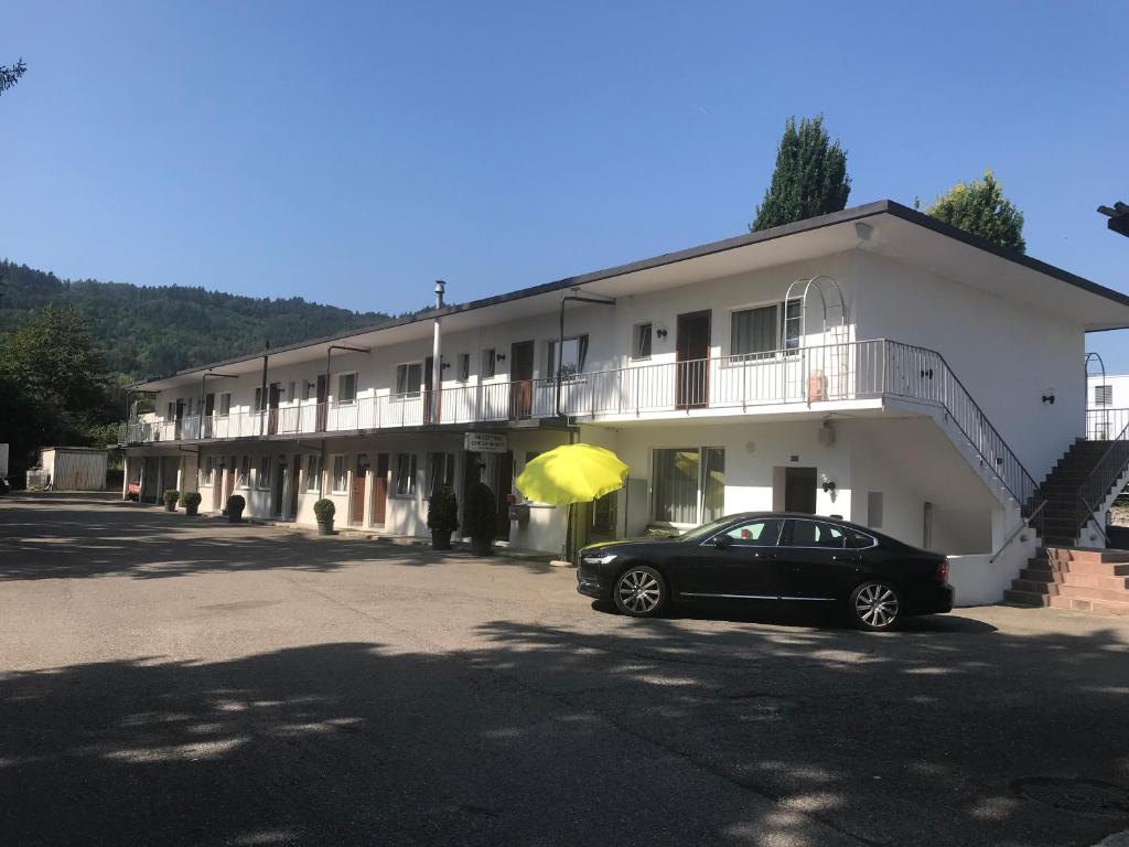 a black car parked in front of a building with a yellow umbrella at Motel City in Spreitenbach