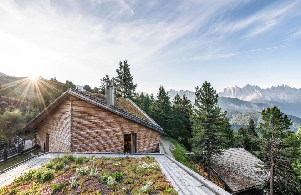 een houten huis op een heuvel met bergen op de achtergrond bij Odles Lodge in Bressanone