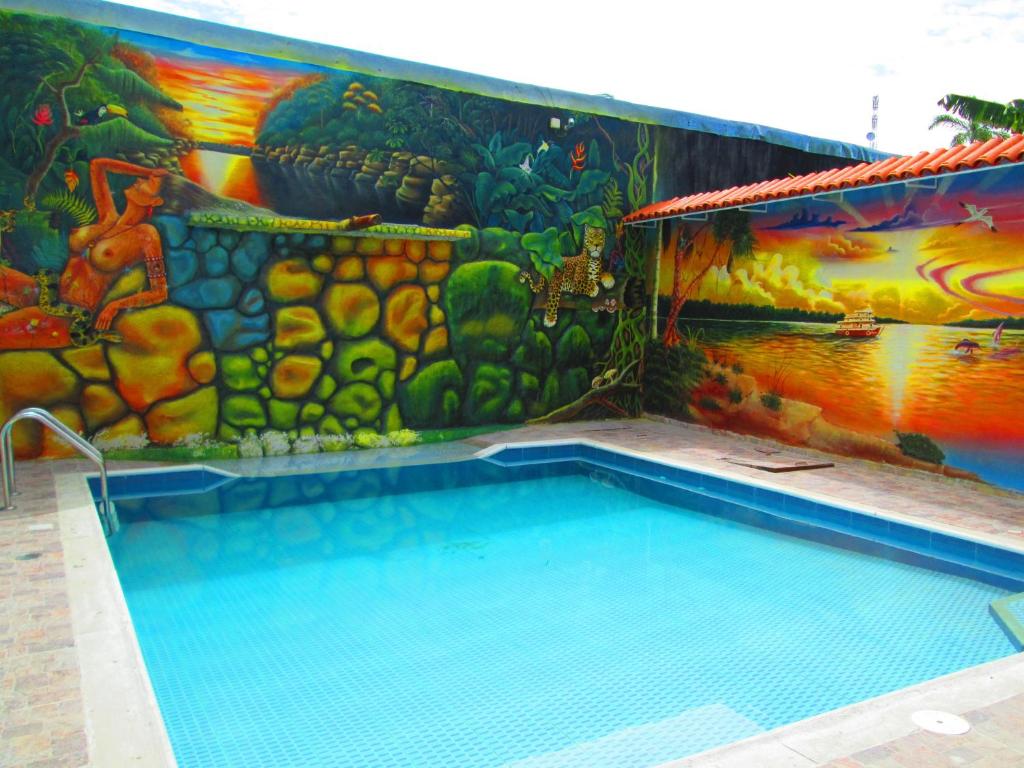 a swimming pool with a mural on the side of a building at Hotel Huito in Leticia