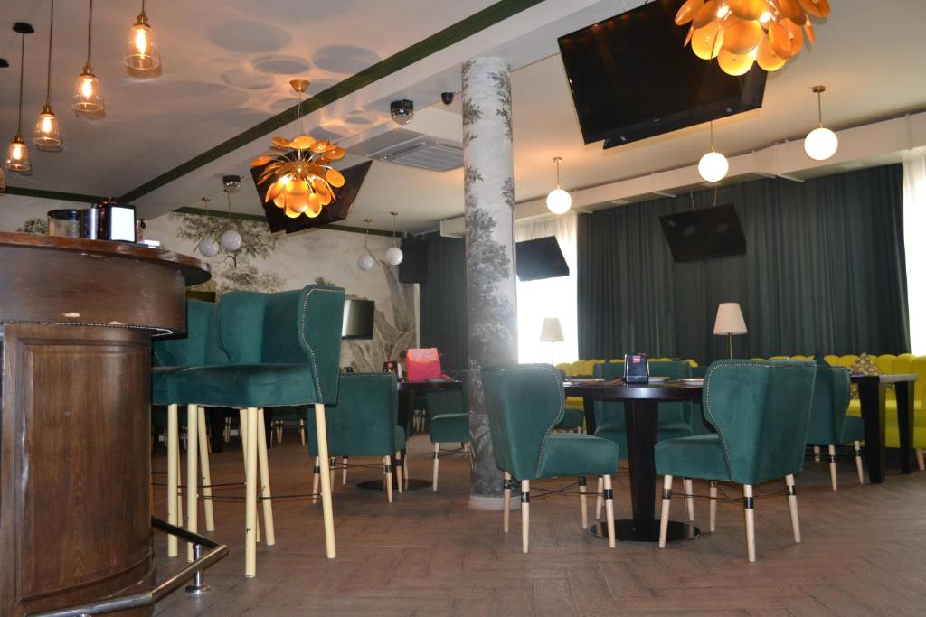 a restaurant with green chairs and a table and a tv at Ayhan Hotel in Aktobe