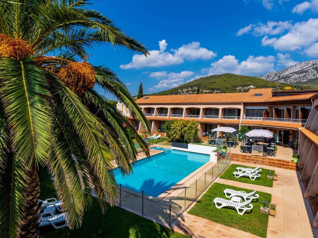 ラ・ヴァレット・デュ・ヴァールにあるNoemys Toulon La Valette - Hotel restaurant avec piscineのヤシの木とスイミングプールを併設するリゾート